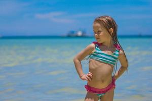 skön liten flicka stående i vatten på de strand foto