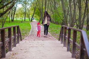 ung mamma som går med sin lilla dotter i höstparken foto