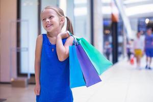 liten mode flicka med paket i en stor handla Centrum foto