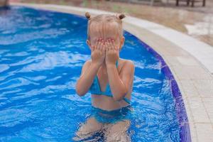 förtjusande liten flicka njut av i de simning slå samman foto