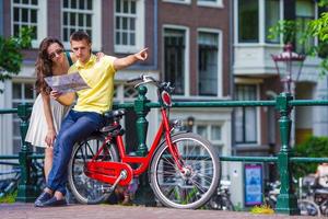 ung turister par ser på Karta med Cyklar i europeisk stad foto