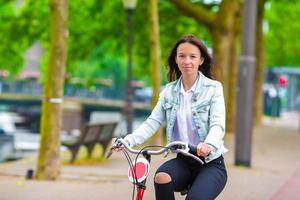 ung Lycklig kvinna på cykel i europeisk stad foto