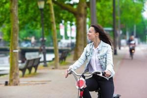 ung Lycklig kvinna på cykel i europeisk stad foto