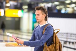 ung man med pass och ombordstigning passerar på de främre skrivbord på flygplats foto