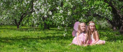 liten förtjusande flickor med fjäril vingar i de blomstrande äpple fruktträdgård foto