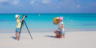 liten flicka framställning Foto av henne mamma och syster på de strand