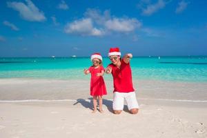 far och dotter i santa hatt på tropisk strand foto