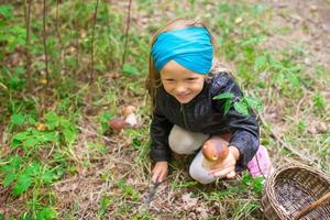 liten söt flicka plocka upp svamp i de skog foto