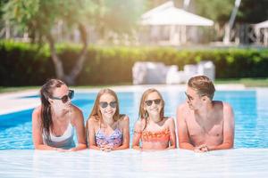 Lycklig familj av fyra i utomhus simning slå samman foto