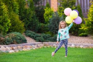 Lycklig liten flicka spelar med ballonger utomhus foto