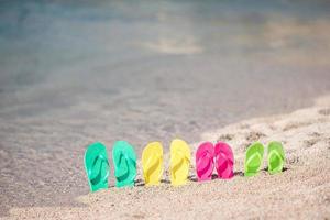 familj färgrik flip flops på strand i främre av de hav foto