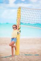 liten förtjusande flicka spelar strand volleyboll med boll. sportig unge njut av strand spel utomhus foto