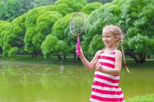 söt liten flicka spelar badminton på picknick foto