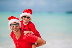 far och dotter i santa hatt ha roligt på tropisk strand foto