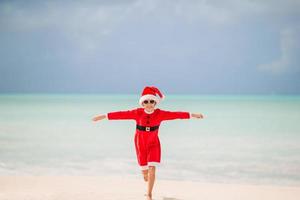 bedårande liten flicka i santa hatt på tropisk strand foto