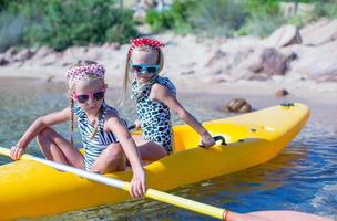 liten förtjusande flickor njuter Kajakpaddling på gul kajak i de klar turkos vatten foto