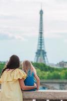 liten förtjusande flicka och henne ung mamma i paris nära eiffel torn under sommar semester foto