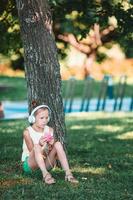 liten förtjusande flicka lyssnande musik i de parkera foto