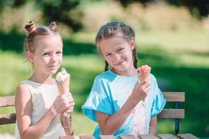 liten flickor äter glass utomhus på sommar i utomhus- Kafé foto