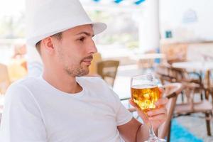 ung man med öl på de strand i utomhus bar foto