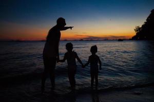 familj av tre silhuett i de solnedgång på boracay strand foto