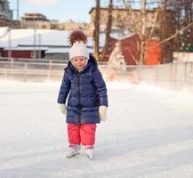 förtjusande liten flicka i de skridsko på vit is foto