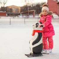 liten Lycklig flicka skridskoåkning på de isbana foto