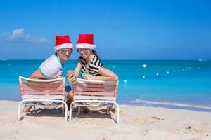 Lycklig par bär santa hatt på karibiska strand foto