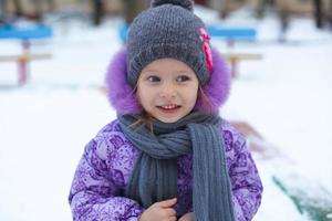 porträtt av liten söt Lycklig flicka har roligt i de snö på en solig vinter- dag foto