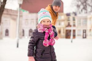 porträtt av den lilla lyckliga flickan tycker om att åka skridskor med sin far foto