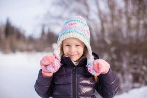 porträtt av liten förtjusande flicka i vinter- hatt på snöig skog foto