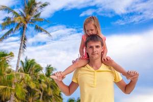liten flicka ha roligt med henne pappa på tropisk strand foto
