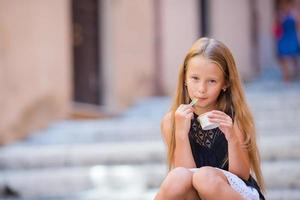 förtjusande flicka äter glass utomhus på sommar i de stad foto