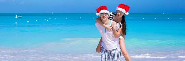 ung romantisk par i santa hattar under strand semester foto