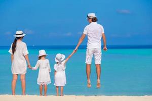 lycklig familj på fyra på vit strand foto