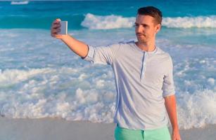 ung man tar selfie på de strand bakgrund de hav foto