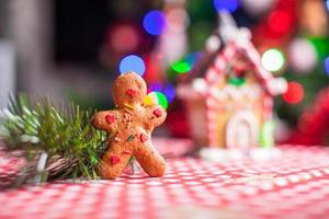 pepparkaka man i främre av hans godis ingefära hus bakgrund de jul träd lampor foto