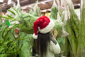 ung kvinna i santa hatt välja jul träd på de marknadsföra foto