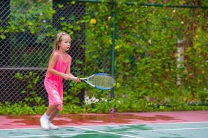 liten flicka spelar tennis på banan foto