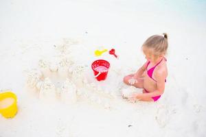bedårande liten flicka som leker med strandleksaker under tropisk semester foto