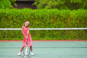 liten flicka spelar tennis på banan foto