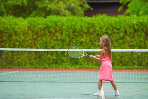 liten flicka spelar tennis på banan foto