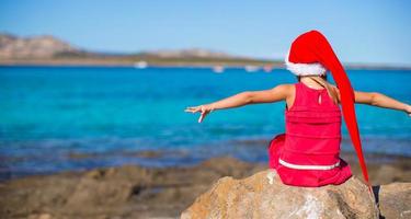 förtjusande liten flicka i jul hatt under strand semester foto