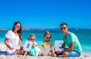 Lycklig familj av fyra under sommar strand semester foto