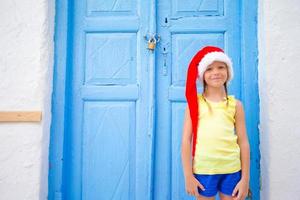 liten flicka i santa hatt utomhus i gammal gata på jul semester i mykonos. foto