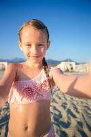 Lycklig liten flicka tar selfie på europeisk strand under sommar semester i Italien foto
