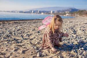 förtjusande liten flicka har roligt på de strand i en vinter- solig dag foto