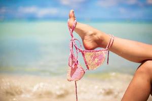 rosa baddräkt på kvinna ben på vit tropisk strand foto