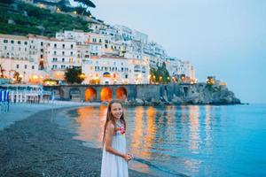 förtjusande liten flicka på solnedgång i amalfi stad i Italien foto