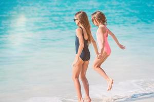 liten Lycklig rolig flickor ha en massa av roligt på tropisk strand spelar tillsammans. foto